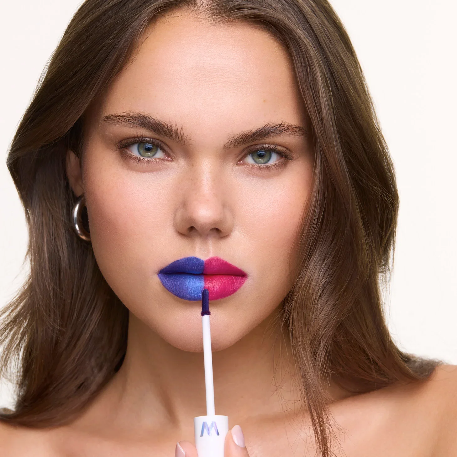 Woman with a blue lip masque on one side of her lips and pink color revealed on the other
