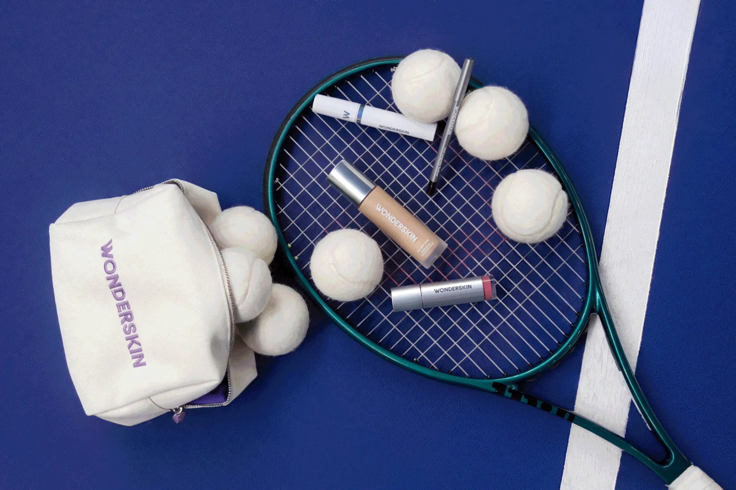 Wonderskin makeup bag, tennis balls and a racket on a blue court