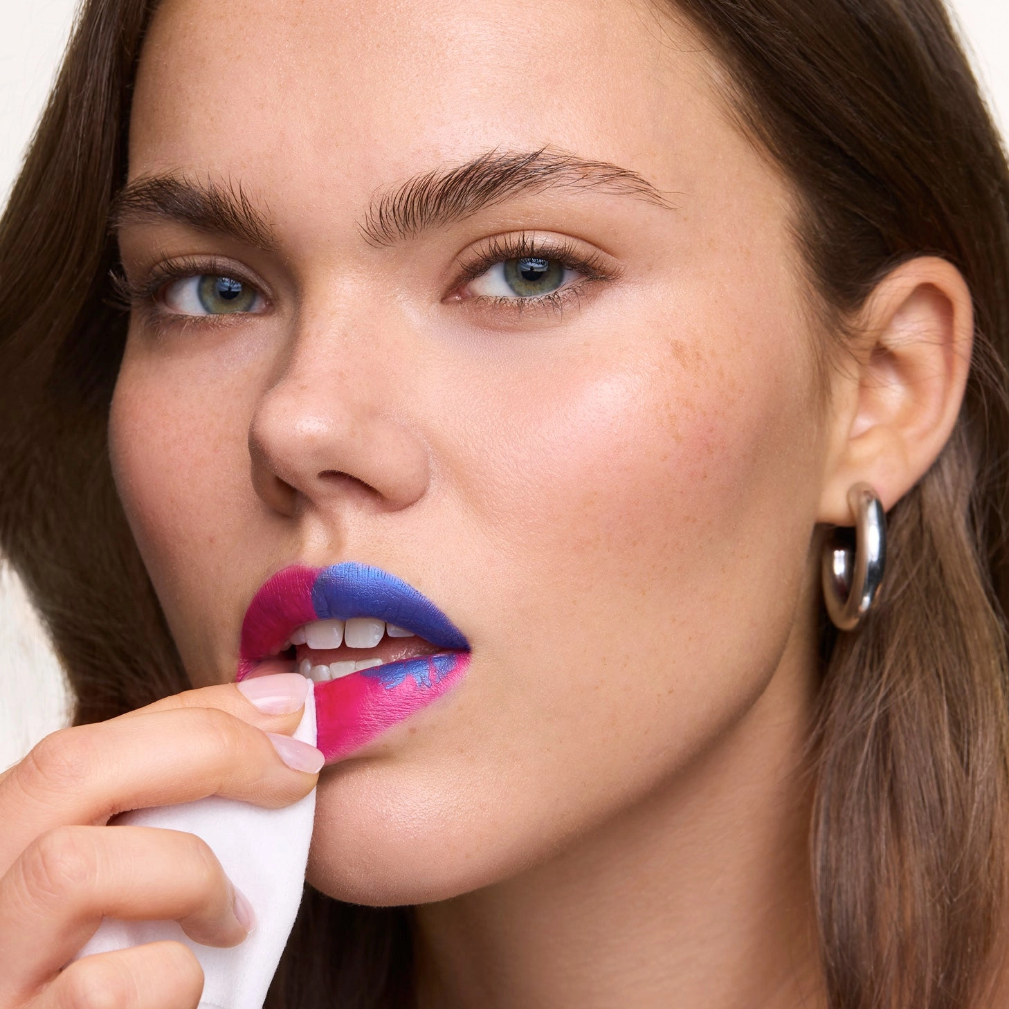Woman peeling a blue film from her lips with a tissue